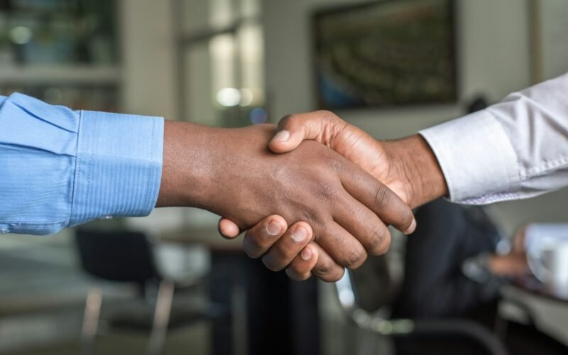 Two people shaking hands at a meeting table