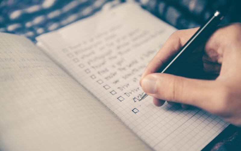 Person planning their day with notebook and phone on desk