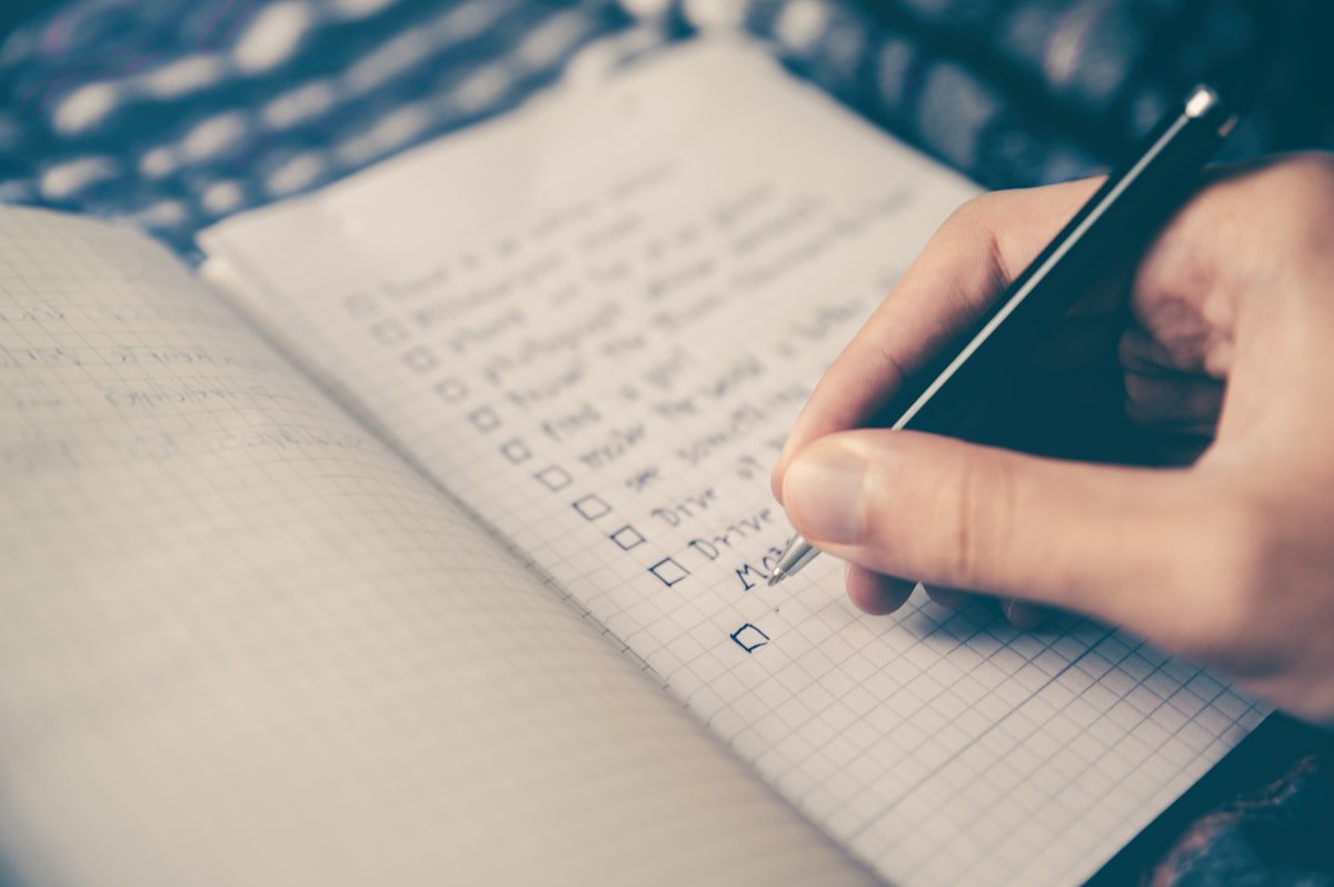 Person planning their day with notebook and phone on desk