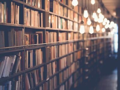A stack of books with notes and a pen