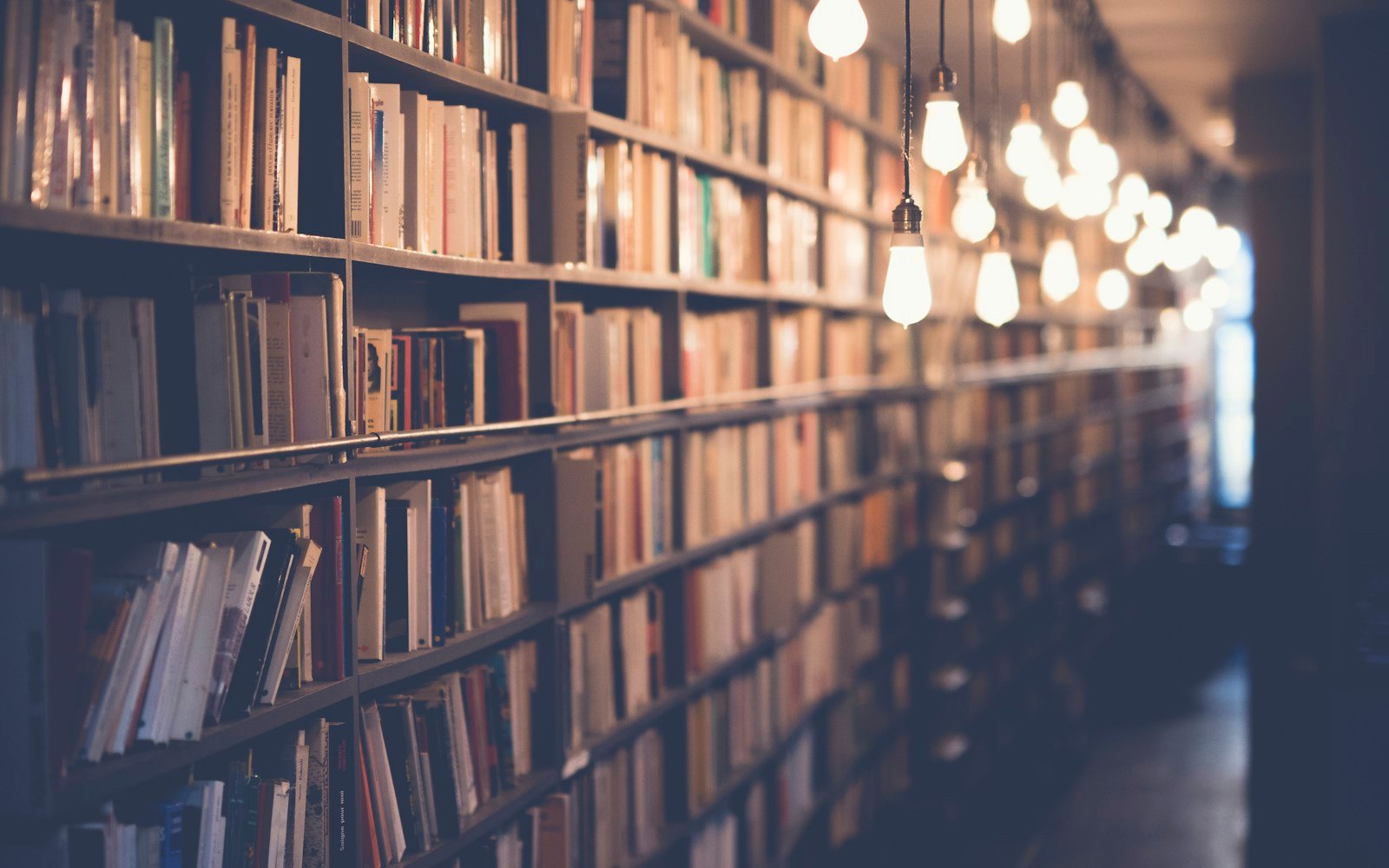 A stack of books with notes and a pen