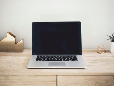 A laptop on a clean desk with notebooks and a coffee cup