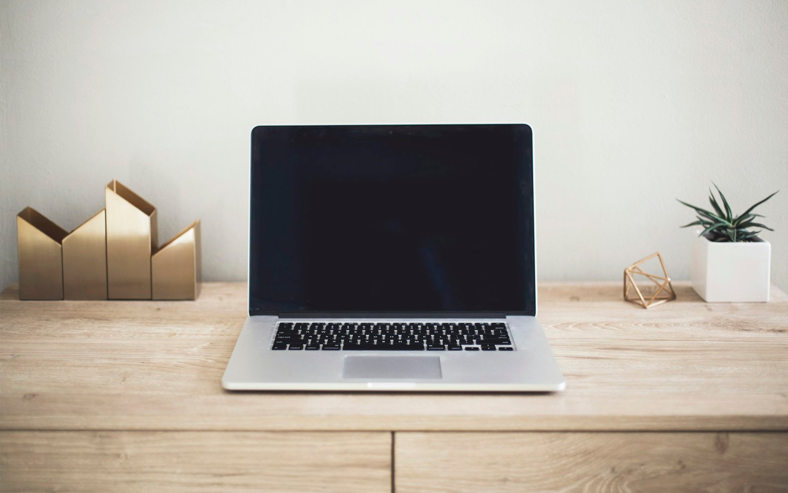 A laptop on a clean desk with notebooks and a coffee cup