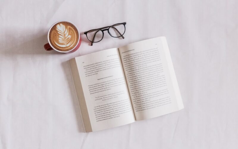 Person reading an eBook on Kindle device with coffee