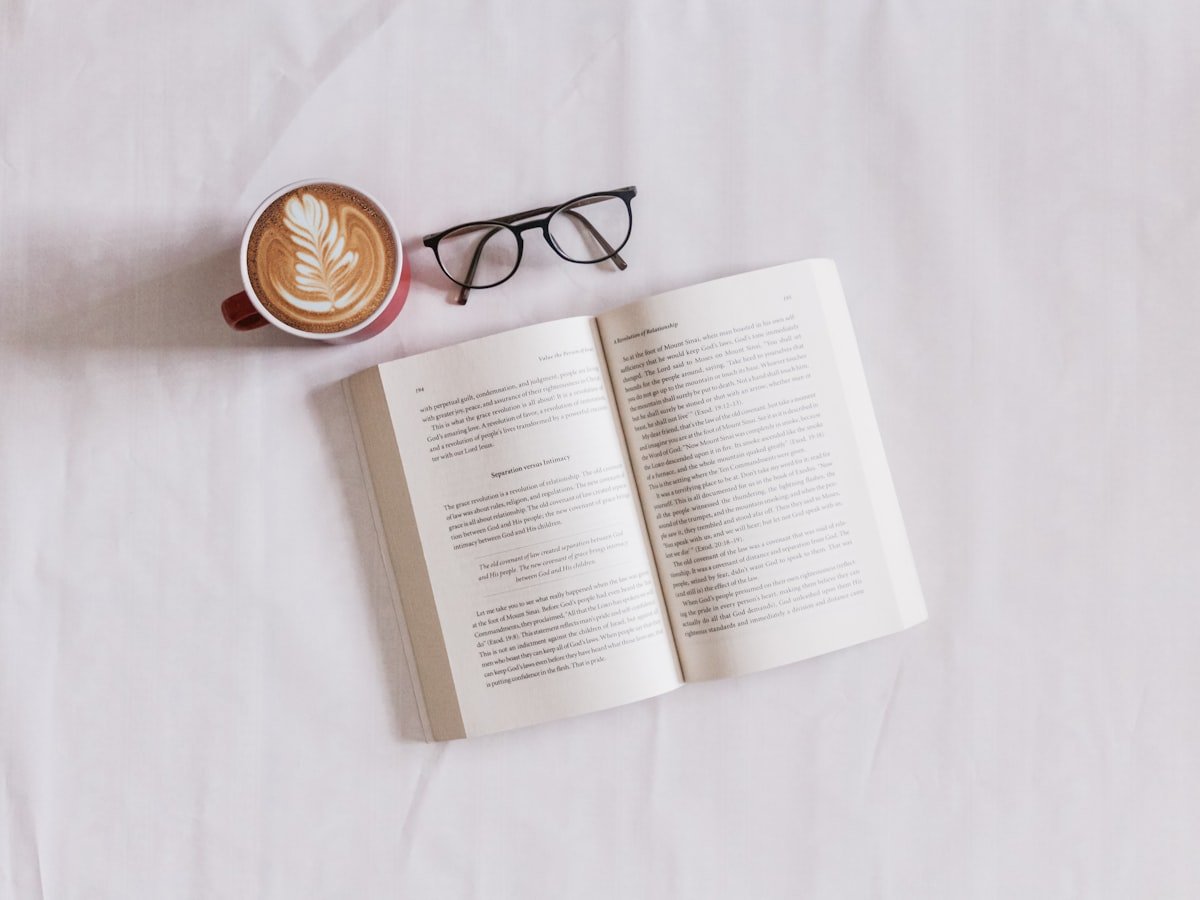Person reading an eBook on Kindle device with coffee